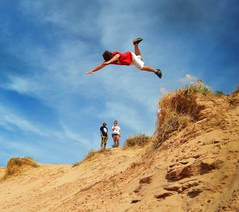 Man jumping off cliff into sand